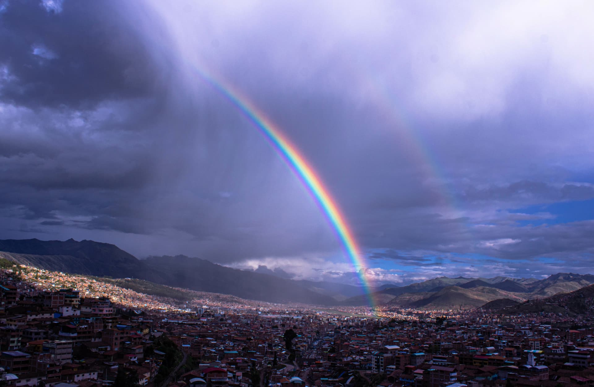 A rainbow over Cusco appears as the rain falls.