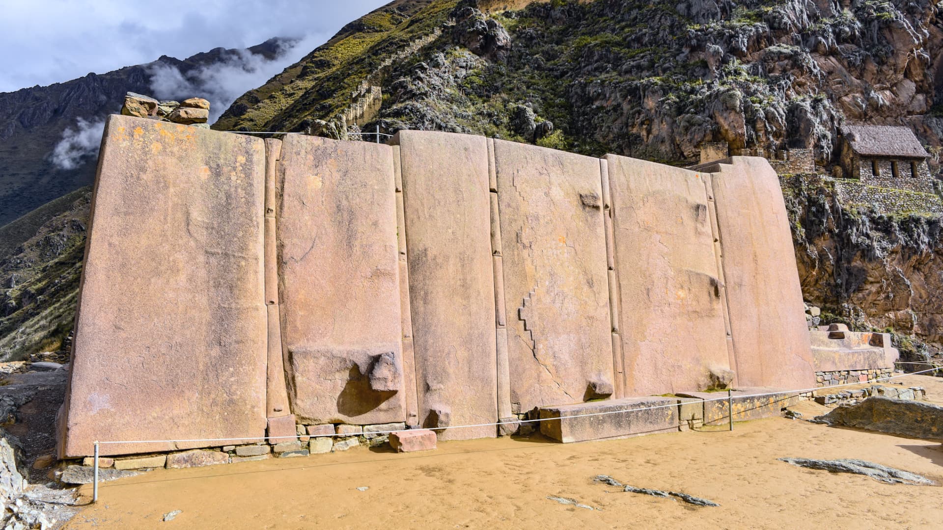 Close-up of large Inca stones at Ollantaytambo, showcasing their precise fitting and impressive size, set against the backdrop of ancient terraces and mountains.